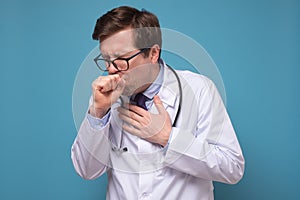 Young ill doctor coughing being ill standing on blue wall