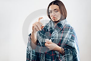 Young ill girl wrapped in blanket uses drops