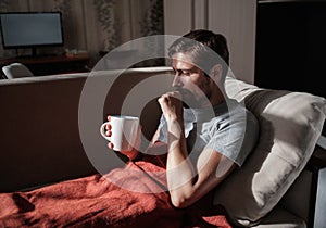 Young ill man drinking hot tea at home