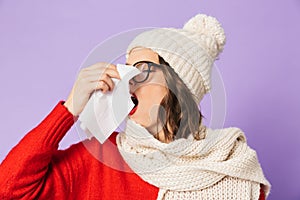 Young ill woman wearing winter hat isolated over purple background holding napkin