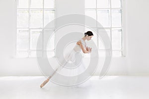 Young and incredibly beautiful ballerina is posing and dancing in a white studio