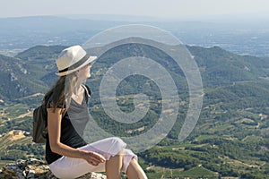 Young independent solo traveler woman sitting and looking at Dentelles de Montmirail mountains, France