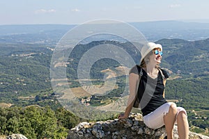 Young independent solo traveler woman sitting and looking at Dentelles de Montmirail mountains, France