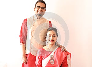 A young indian bengali assamese married couple dressed in red and white ethnic indian dress and smiling