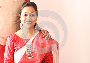 A young indian bengali assamese married lady dressed in red and white saree and smiling