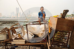 Young Indian boy making faces on the pile of trash in Mumbai, India