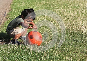 Young Indian boy playing in grass with ball