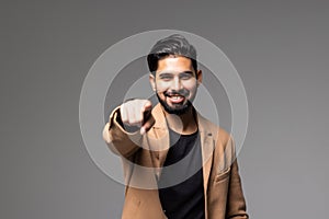 young indian business man pointing and looking at the camera. on a gray background