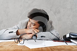 Young indian businessman sleeping at table while working in office