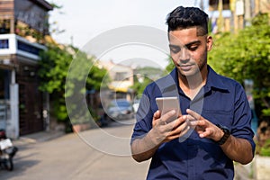 Young Indian businessman using mobile phone in the streets outdo