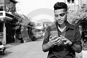 Young Indian businessman using mobile phone in the streets outdoors