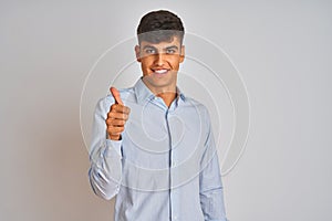 Young indian businessman wearing elegant shirt standing over isolated white background doing happy thumbs up gesture with hand