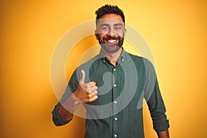 Young indian businessman wearing elegant shirt standing over isolated white background doing happy thumbs up gesture with hand