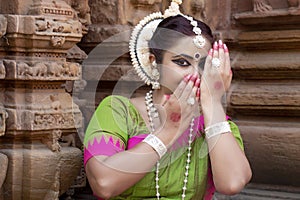 A young Indian classical odissi dancer hiding face with hands