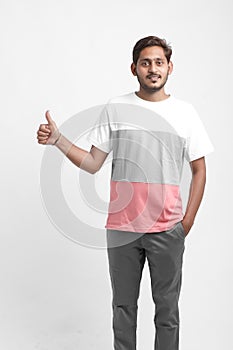 Young indian college student showing thumps up on white background