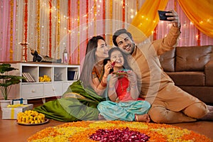 Young Indian couple with their daughter celebrating diwali at home - Indian festival, hindu festival.