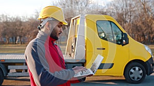 Young Indian engineer wearing safety helmet holding a laptop and working