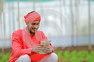 young indian farmer counting money at greenhouse or polyhouse