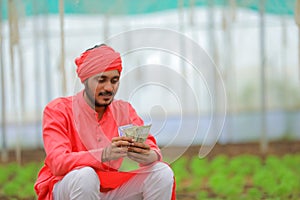 young indian farmer counting money at greenhouse or polyhouse