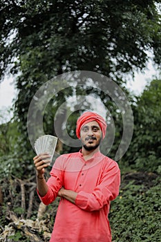 Young indian farmer counting and showing money