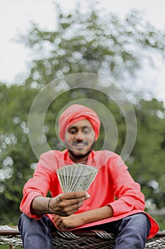 Young indian farmer counting and showing money