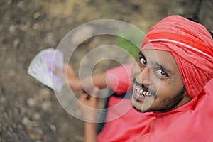 Young indian farmer counting and showing money