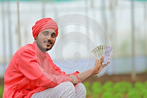 young indian farmer counting and showing money at greenhouse or polyhouse