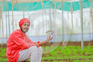 young indian farmer counting and showing money at greenhouse or polyhouse