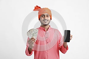 Young indian farmer using smartphone and showing money on white background