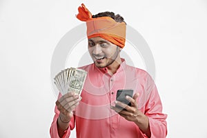 Young indian farmer using smartphone and showing money on white background