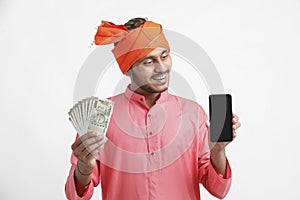 Young indian farmer using smartphone and showing money on white background