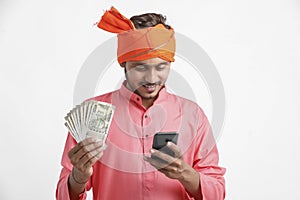 Young indian farmer using smartphone and showing money on white background