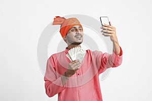 Young indian farmer using smartphone and showing money on white background