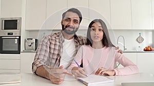 Young indian father and daughter having online lesson together at home.