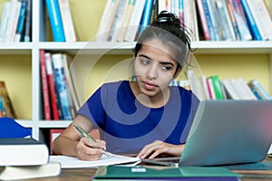 Young indian female student learning with books and computer