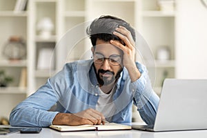 Young Indian Freelancer Man Checking Working Schedule In Notepad At Home