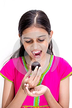 Young indian girl eating a gulab jamun - an indian sweet