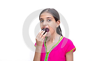 Young indian girl eating a gulab jamun - an indian sweet