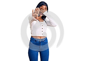 Young indian girl wearing casual clothes covering eyes with hands and doing stop gesture with sad and fear expression