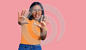 Young indian girl wearing casual clothes and glasses afraid and terrified with fear expression stop gesture with hands, shouting