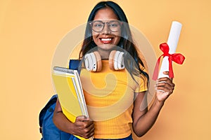 Young indian girl wearing student backpack holding diploma smiling with a happy and cool smile on face