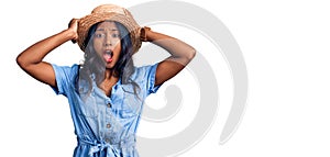 Young indian girl wearing summer hat crazy and scared with hands on head, afraid and surprised of shock with open mouth