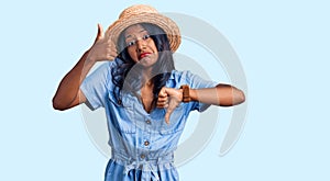Young indian girl wearing summer hat doing thumbs up and down, disagreement and agreement expression