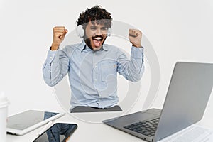 Young indian glad celebrates with raised arms