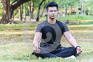 Young indian guy practicing yoga in the park Serene yoga man practitioner workout and sitting in lotus pose or asana with