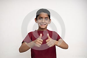 Young indian kid showing thumbs up into the camera while smiling. Small kid education concept