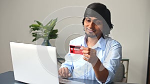 Young indian man with credit card in hands making purchases online