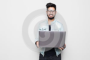 Young indian man in eyesglasses and casual wear holding laptop white standing isolated on white background