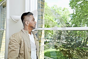 Young Indian man looking out window