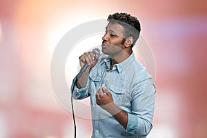 Young indian man performing lyric song on abstract pink bokeh background.